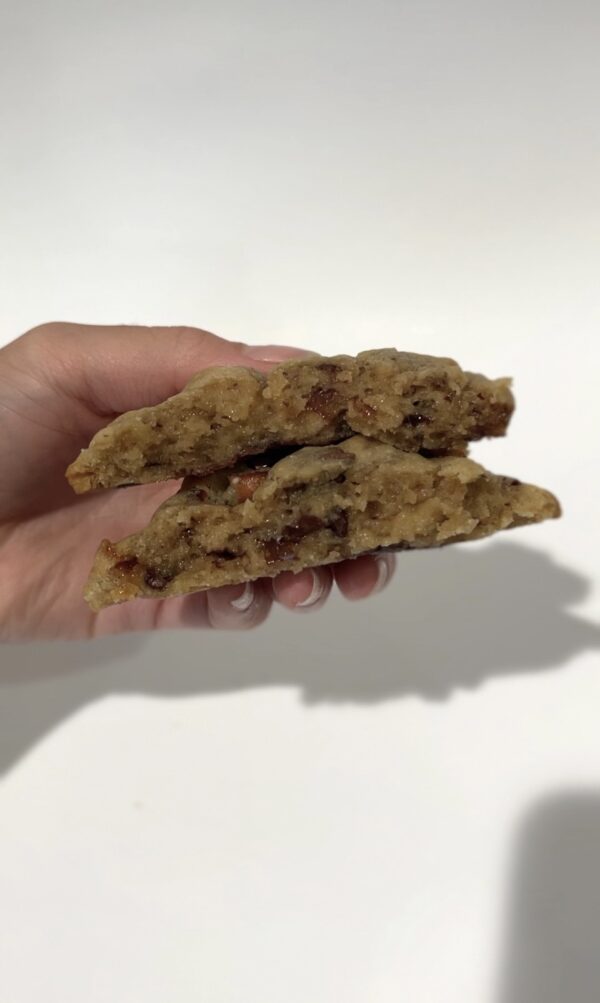 Chewy salted caramel pretzel cookie with golden brown edges, gooey caramel bits topped with crunchy pretzel twists and flaky sea salt