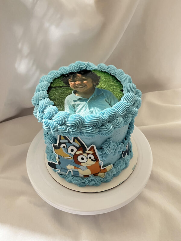 Angle view of a custom photo baby shower cake with smooth buttercream frosting, piped borders, and an edible printed photo topper, designed for personalized birthday or baby shower celebrations, perfect for custom party desserts.