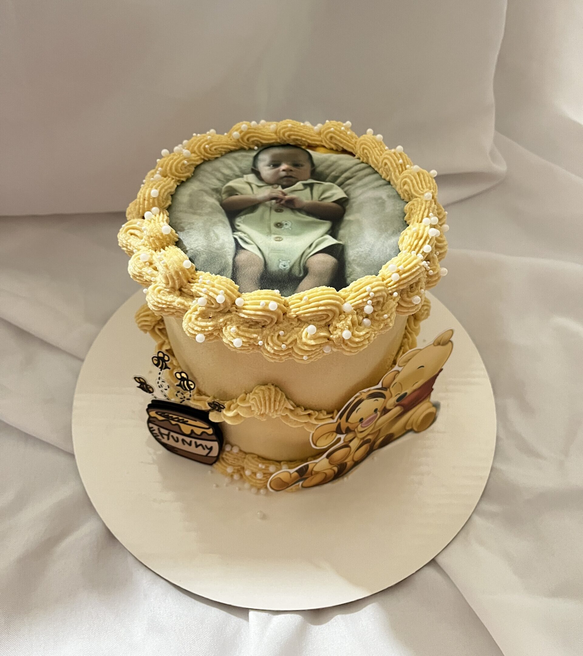 Side view of a custom photo baby shower cake with smooth buttercream frosting, piped borders, and an edible printed photo topper, designed for personalized birthday or baby shower celebrations, perfect for custom party desserts.