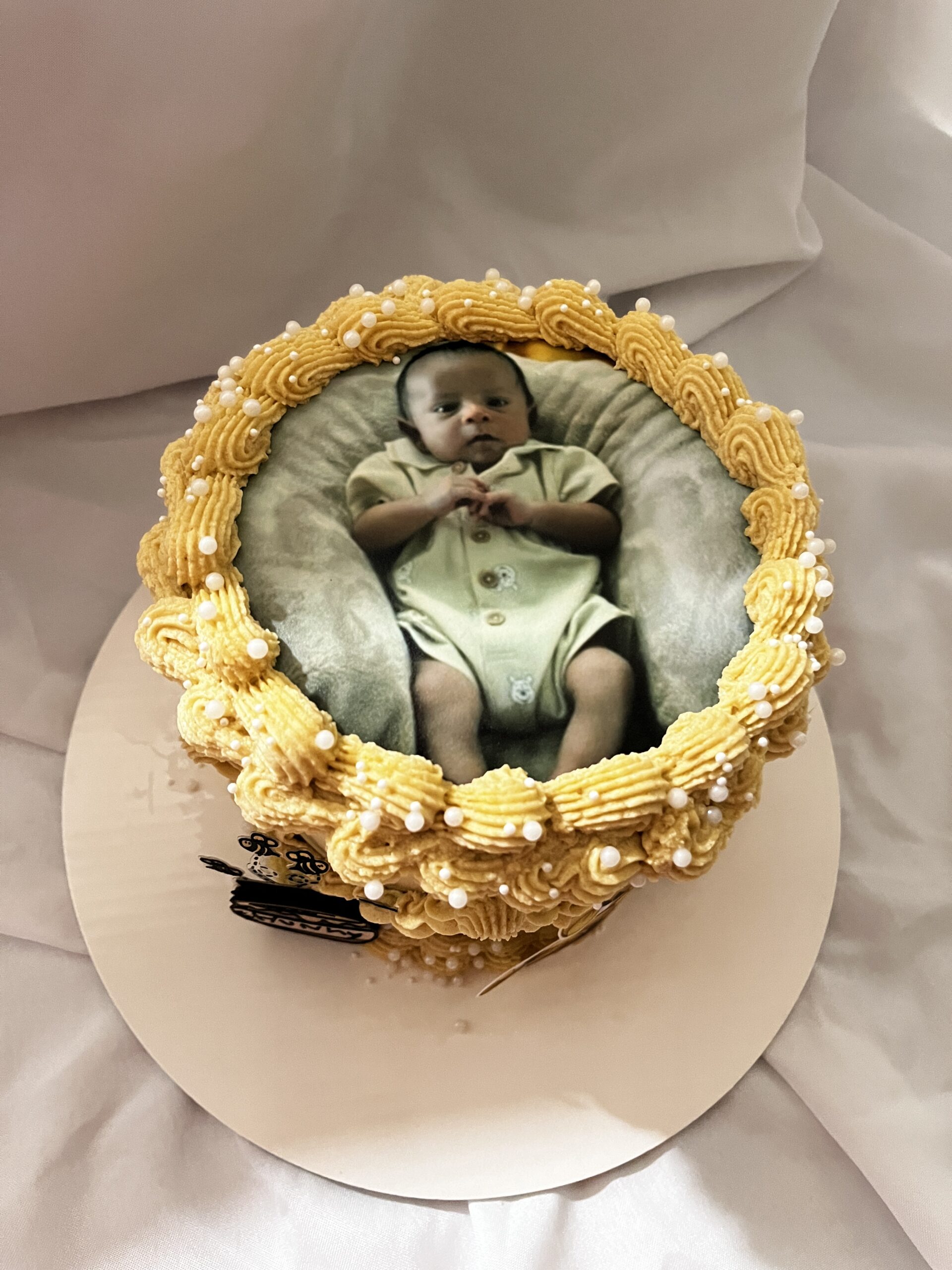 Top view of a custom photo baby shower cake with smooth buttercream frosting, piped borders, and an edible printed photo topper, designed for personalized birthday or baby shower celebrations, perfect for custom party desserts.