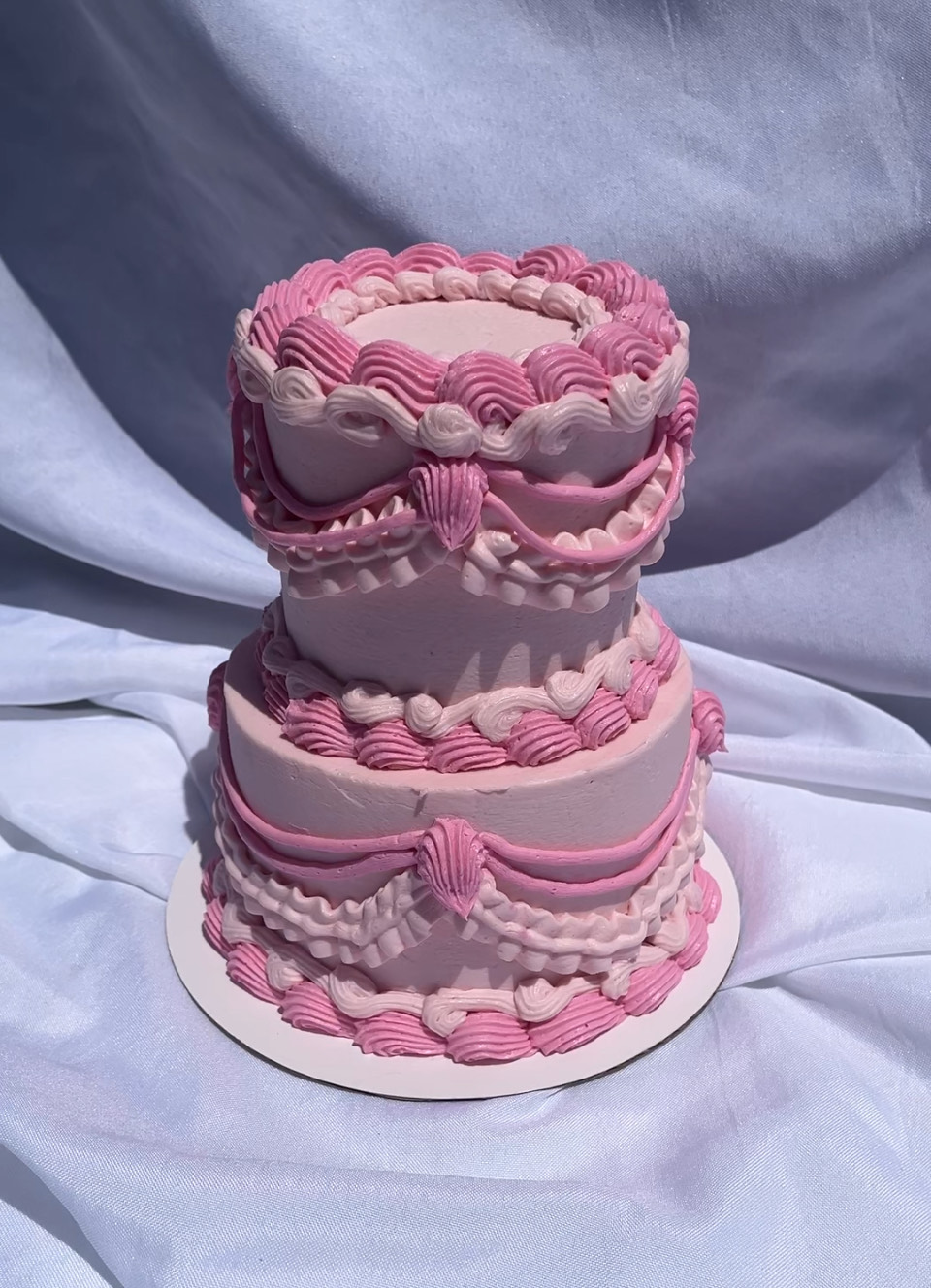 pink two tier vintage inspired coquette celebration cake with elegant piping details, decorated in a romantic and feminine style